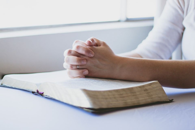Praying hands resting on a BIble