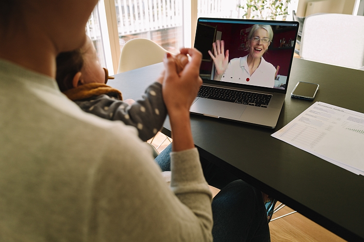 Woman with her daughter having video call with her mother. Woman connecting with her mother on a video call while at home.