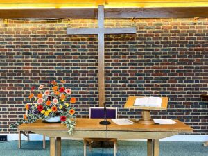 The communion table with the cross behind and flowers on the table