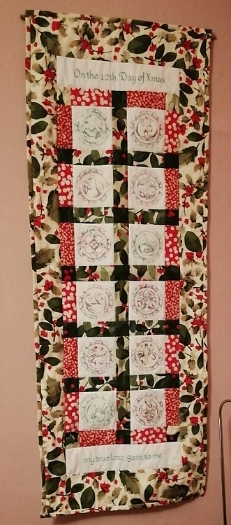 An embroidered wall hanging illustrating the 12 days of Christmas