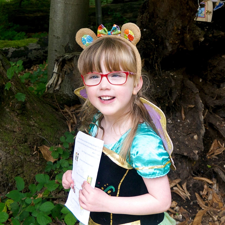 A smiling girl wearing teddy bear eats and a princess dress