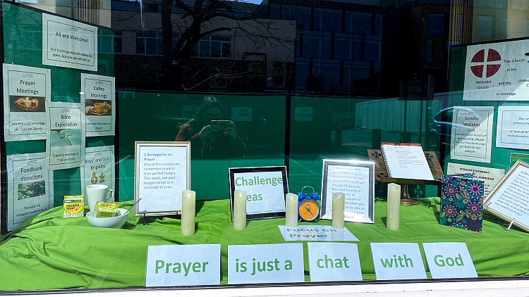 A window display showing some prayer challenges and the words "prayer is just a chat with God"