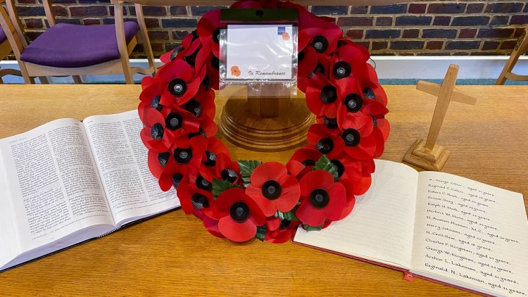 A poppy wreath in the centre of a communion table with an open BIble on one side and a book of remembrance on the other