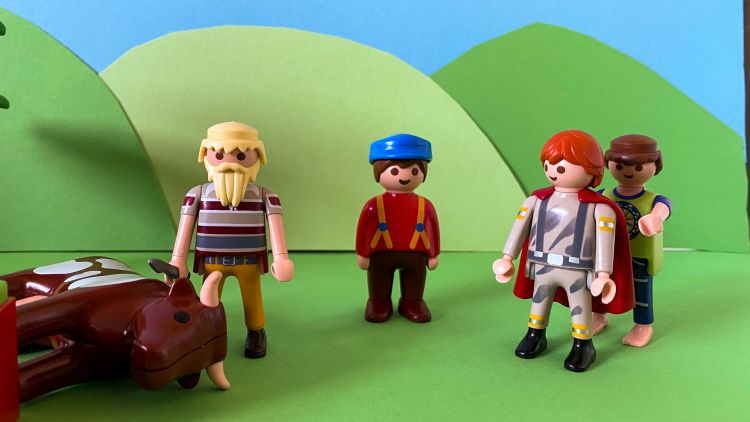 A Playmobil scene depicting the prodigal son with a cloak around him and the fatted calf being killed