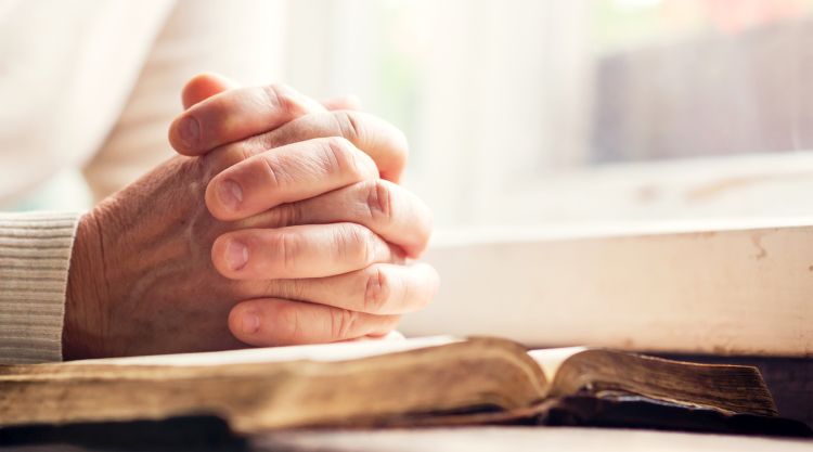 Hands of a man praying over a Bible