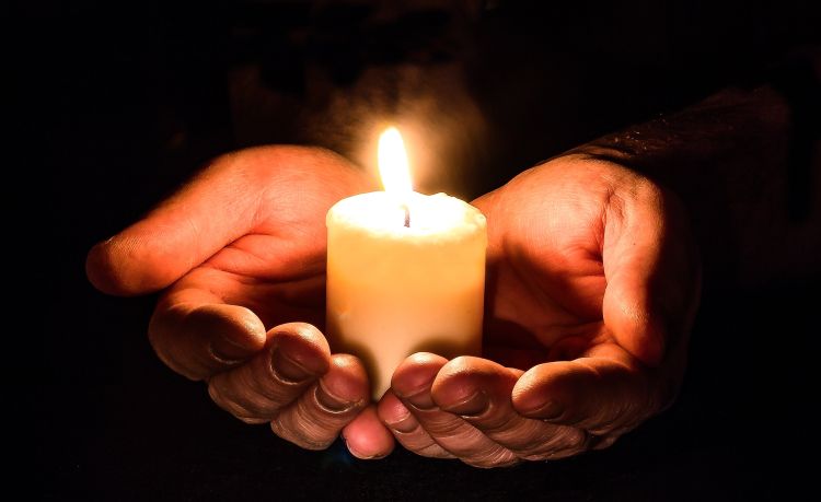 Cupped hands holding a lit candle
