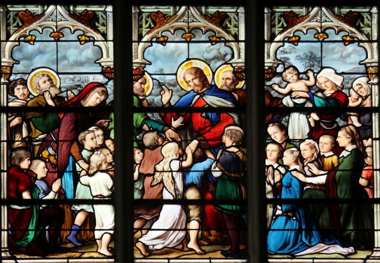 A stained glass window depicting Jesus surrounded by children