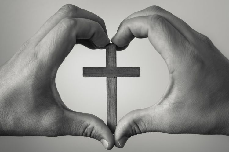 Hands making heart symbol with cross in the centre