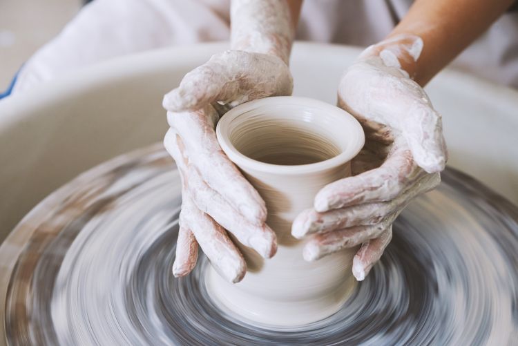 Hands shaping clay on a pottery wheel