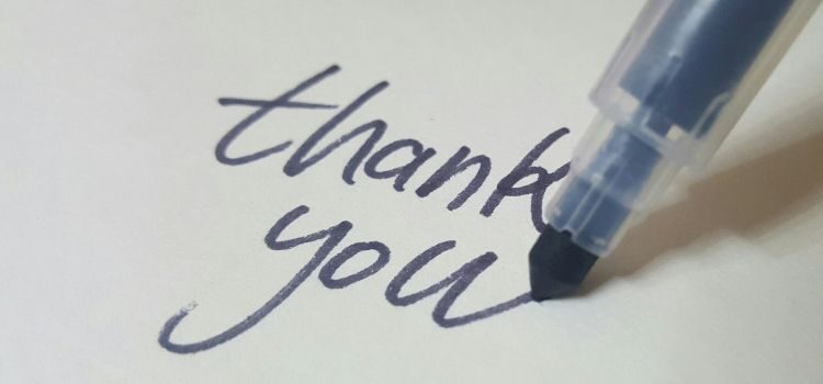 The words 'thank you' being written with a blue pen