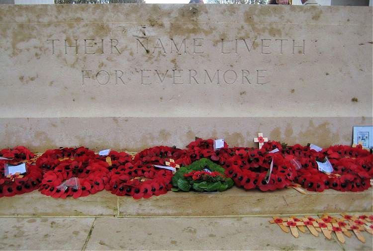 Poppy wreaths at the foot of a memorial with the words 'Their name liveth for evermore.'