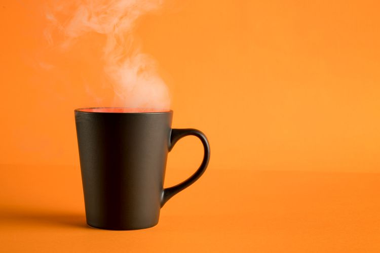 Black coffee cup with steam on orange background.