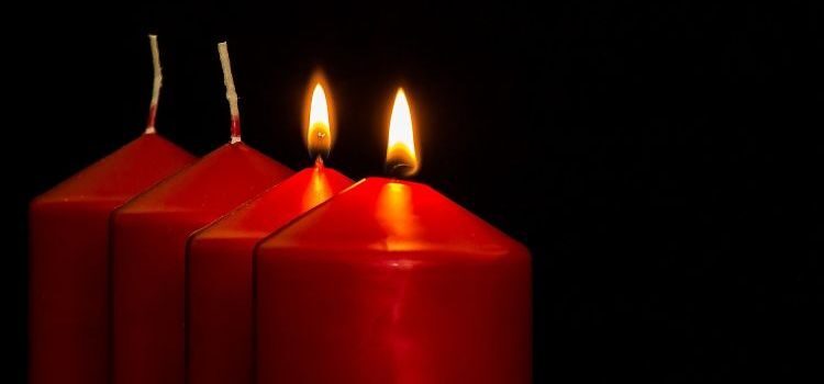 Four red candles against a black background; two of them are lit