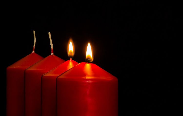 Four red candles against a black background; two of them are lit