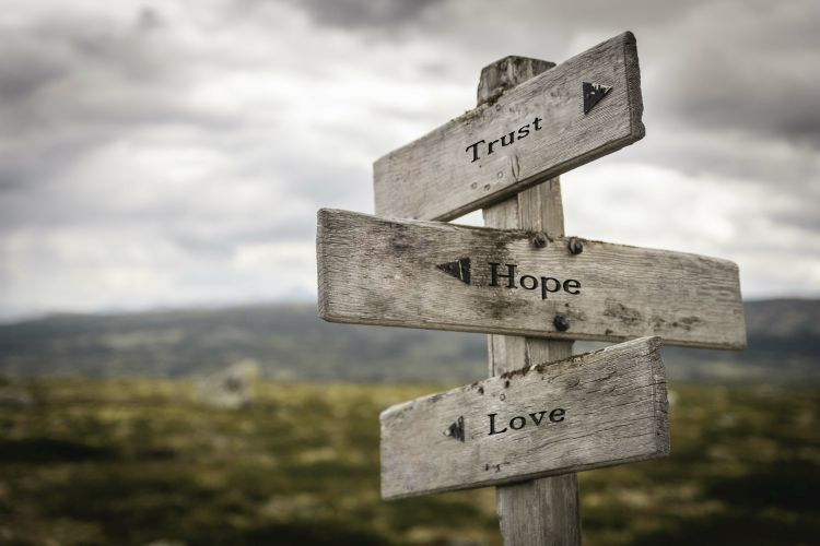 The words 'trust', 'hope' and 'love' on a signpost