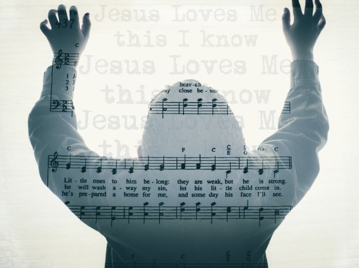 Music for 'Jesus loves me' with a person overlaid on top, their arms lifted in praise