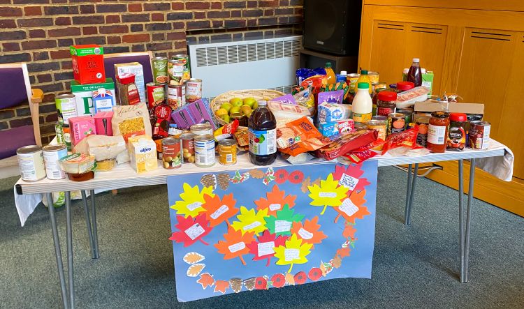 A table filled with food being donated to the foodbank at the front of the church during a harvest service