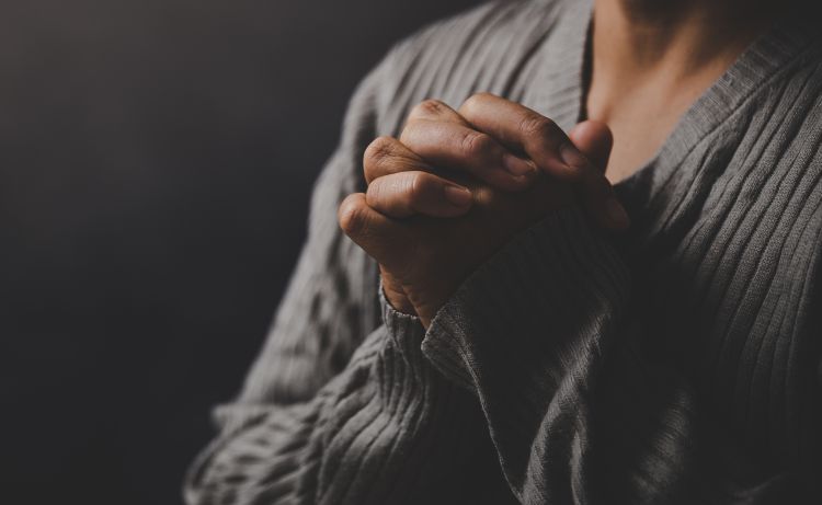 A person clasping their hands in prayer