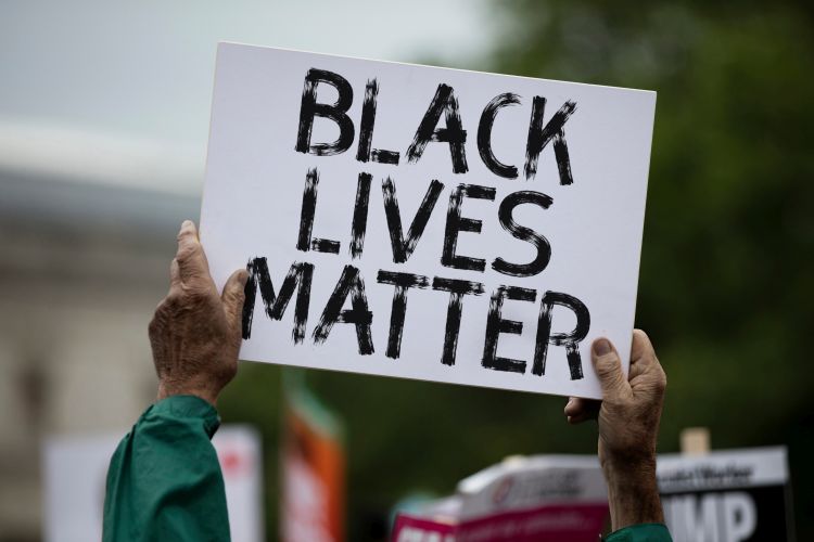 A person holding a black lives matter banner at a protest