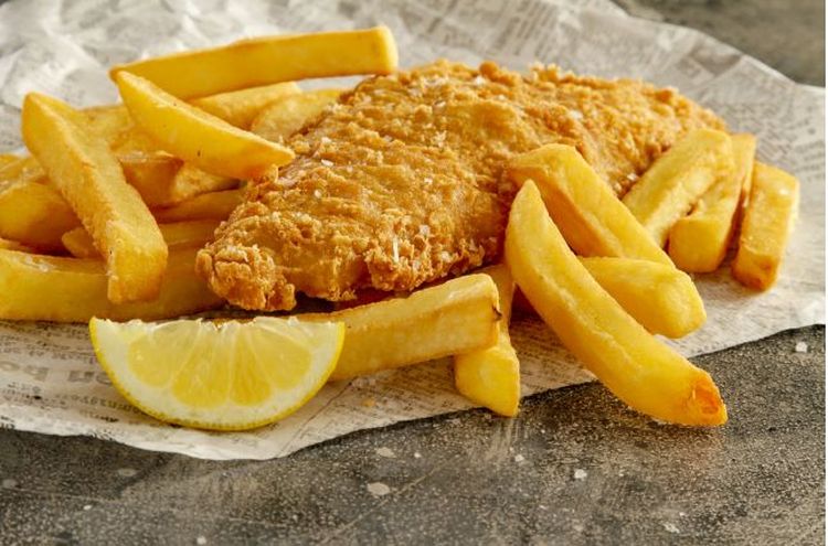 Fish and chips with a lemon wedge on a sheet of greaseproof paper