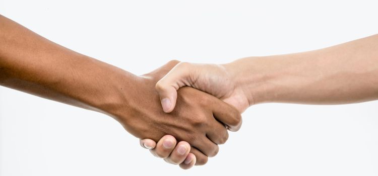 A handshake between a white person and a person of colour