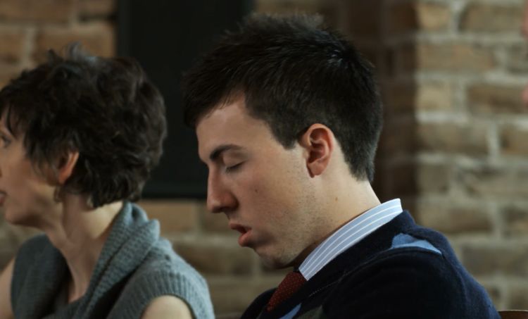 A man falling asleep in a meeting with a woman sitting next to him