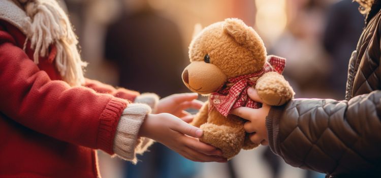 A child's hand receiving a teddy bear at a charity event